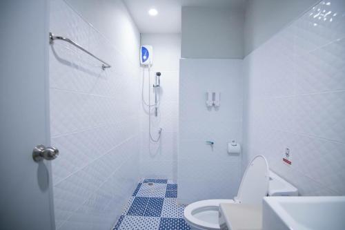 La salle de bains blanche est pourvue d'une douche et de toilettes. dans l'établissement PJ Loft Hotel, à Ban Khok Krathin