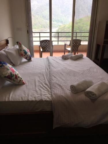 a white bed with pillows and a large window at Aloha Apartments by blissful Ganges in Rishīkesh