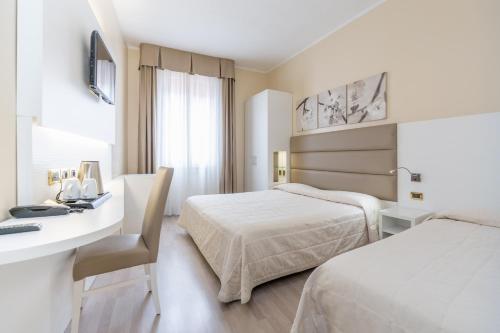 um quarto de hotel com duas camas e uma secretária em Hotel University em Bolonha
