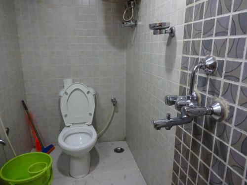 La salle de bains est pourvue de toilettes et d'un seau vert. dans l'établissement Monovilla Inn, à Kolkata