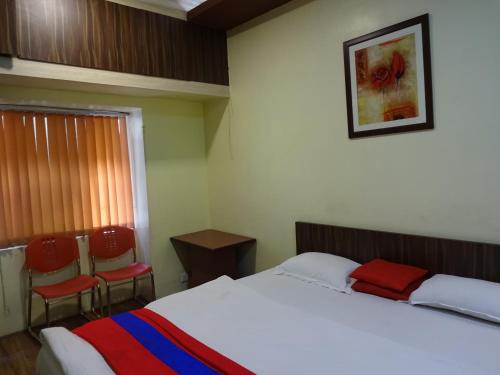 a bedroom with a bed and two chairs at Monovilla Inn in Kolkata