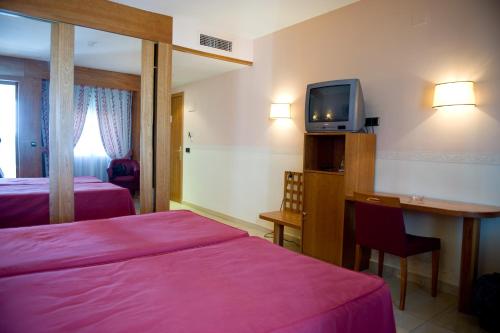 a hotel room with two beds and a desk and a tv at Hotel La Maruxiña in La Alameda de la Sagra