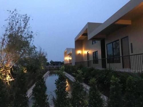a house with a pond in front of it at The Residence Thepkanjana in Ban Khlong Krathum Baen