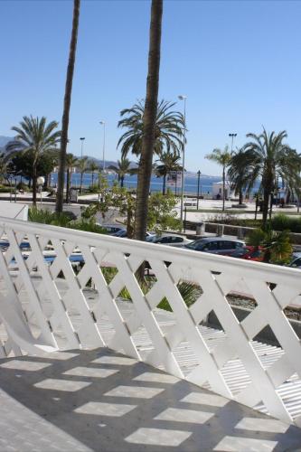 a white fence in front of a beach with palm trees at Las Américas - Mares in Torre del Mar