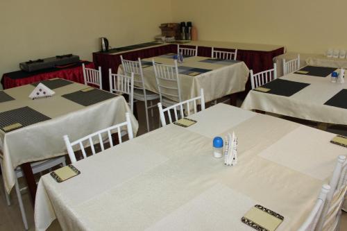 a dining room with white tables and white chairs at Gees Inn in Nakuru