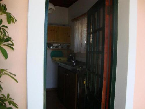 een keuken met een deur naar een keuken met een wastafel bij Anthimos Rooms in Paleokastritsa