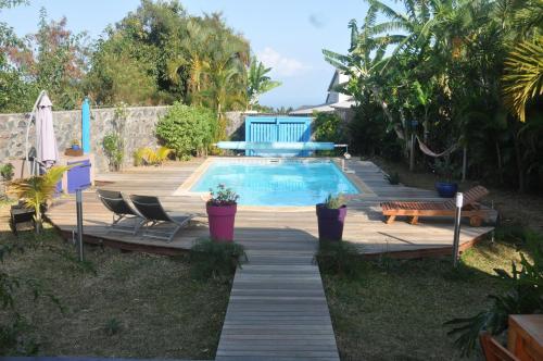 a swimming pool in a backyard with chairs and a wooden walkway at Ti Joli Caz en Bois in Saint-Gilles-les Hauts