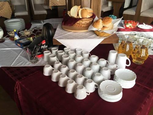 a table with a bunch of cups and plates on it at B&B Villa Pipacs in Feketić