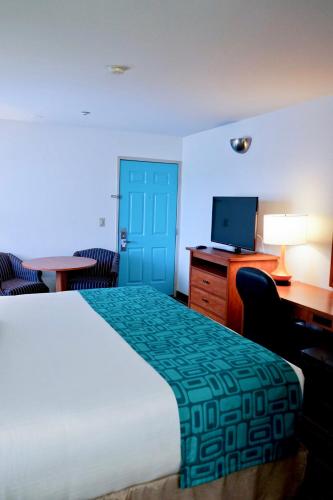a hotel room with a bed and a desk and a television at Howard Johnson by Wyndham Salinas in Salinas