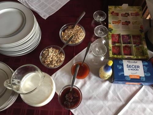 a table with plates and bowls of food and utensils at B&B Villa Pipacs in Feketić