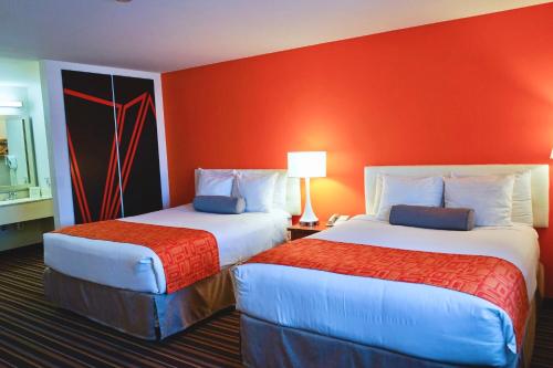 two beds in a hotel room with red walls at Howard Johnson by Wyndham Salinas in Salinas