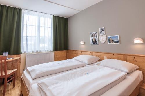 a bedroom with two beds and a table and a window at JUFA Hotel Bad Aussee in Bad Aussee