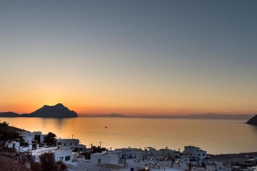 a view of a city with the sun setting over the water at Erisimo in Aegiali