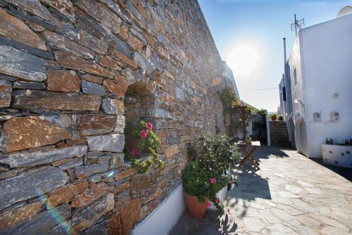 a stone wall with plants and flowers next to a building at Erisimo in Aegiali
