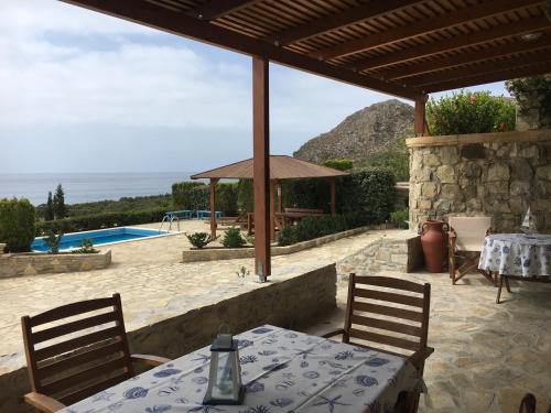 a patio with a table and chairs and a pool at Krinakia Villas in Xerokampos