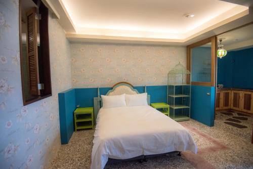 a bedroom with a bed with blue walls and white sheets at Ripoll'es Homestay in Chishang