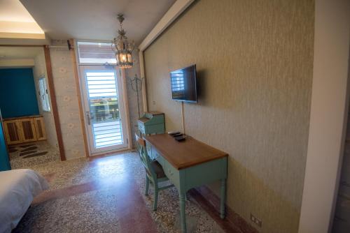 a bedroom with a desk with a television on a wall at Ripoll'es Homestay in Chishang