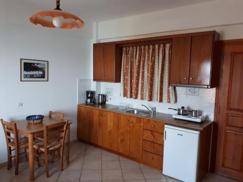 a kitchen with wooden cabinets and a table and a sink at Thalina Hotel in Marathokampos