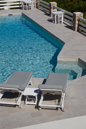 two lounge chairs next to a swimming pool at 9 Muses Exclusive Apartments in Grikos