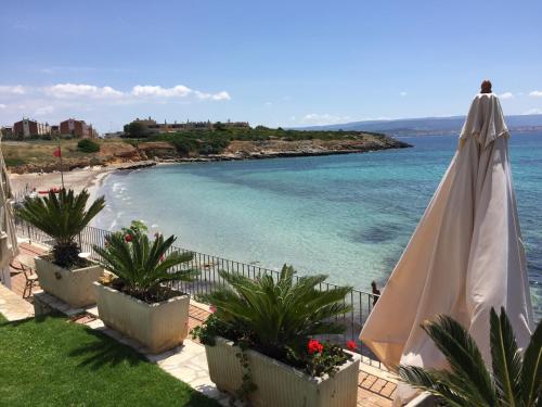 a white umbrella sitting next to a beach at Hotel Punta Negra in Alghero