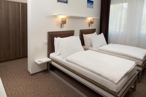 dwa łóżka w pokoju z białymi prześcieradłami i poduszkami w obiekcie Skyhotel Prague w Pradze