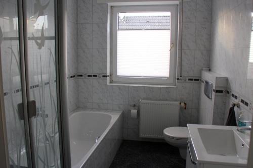 La salle de bains est pourvue d'une baignoire, de toilettes et d'un lavabo. dans l'établissement FeWo-Nordwalde, à Nordwalde