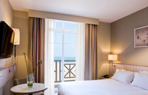 a hotel room with a bed and a large window at Antinéa in Saint Malo