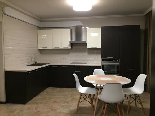 eine Küche mit weißen Schränken sowie einem Tisch und Stühlen in der Unterkunft Apartment Viva in Kiew