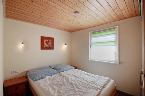 a small bedroom with a bed and a window at Bungalowpark Zinglingsberg by Rujana in Binz