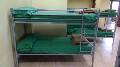 three bunk beds in a room with green sheets at Albergue Los Caminantes 2 in Arzúa