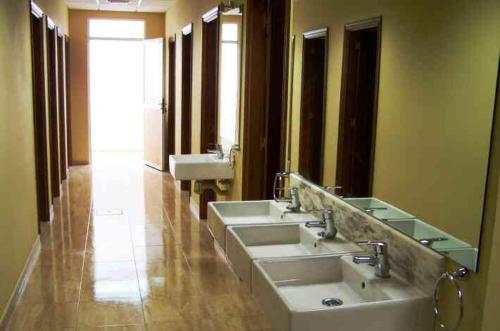 a bathroom with three sinks and two mirrors at Albergue Los Caminantes 2 in Arzúa