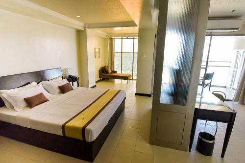 Hotel Tavern Surigao في مدينة سوريجاو: غرفة نوم بسرير كبير ومكتب فيها