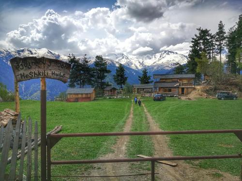 a sign in a field with mountains in the background at Heshkili huts and cabins Svaneti in Keshkili