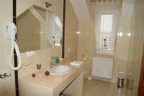 a bathroom with a sink and a shower with a mirror at Pokoje Gościnne Gum-Bar in Biskupice