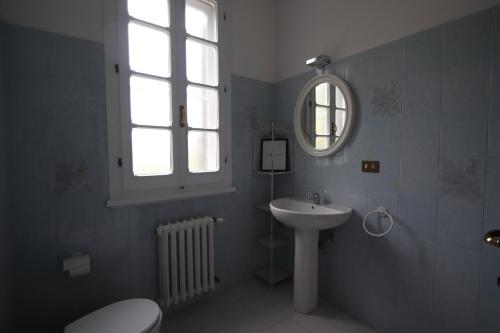 een badkamer met een wastafel, een toilet en een spiegel bij La Casa nel Bosco in Savio di Ravenna