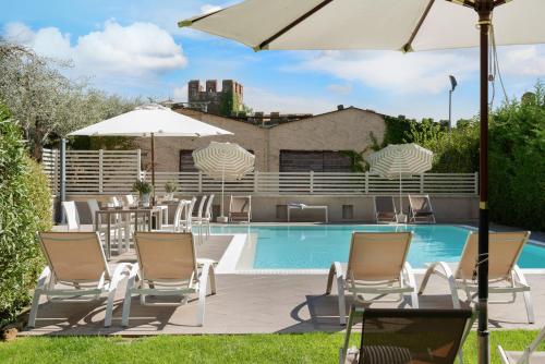 a group of chairs and an umbrella next to a pool at Vialeromadodici Rooms & Apartments in Lazise