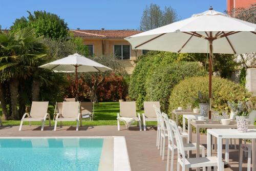 a pool with white chairs and umbrellas and tables and a pool at Vialeromadodici Rooms & Apartments in Lazise