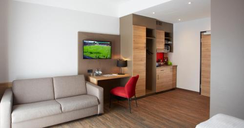 a living room with a couch and a desk with a television at Hotel & Restaurant Wilder Mann in Aalen