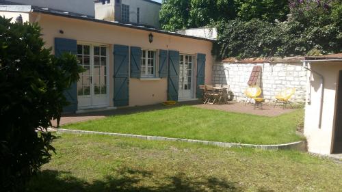 a house with a yard with chairs and a table at Magnolia Cottage in Maisons-Laffitte