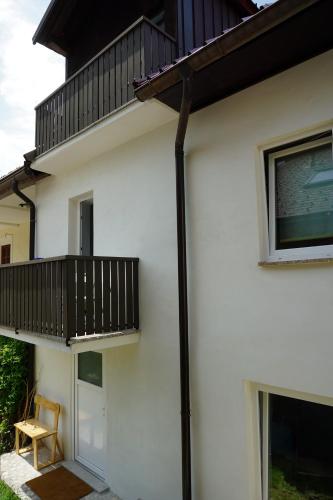 Corner Apartments في بوفيك: منزل أبيض به شرفة وكرسي