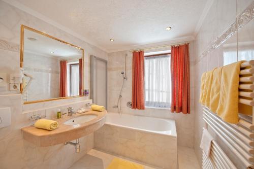 La salle de bains est pourvue d'un lavabo, d'une baignoire et d'un miroir. dans l'établissement Hotel Jagdhof Bed & Breakfast, à Obergurgl