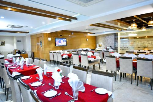 ein Restaurant mit roten Tischen und Stühlen sowie einem TV in der Unterkunft Hotel Amit Park International in Bhilai