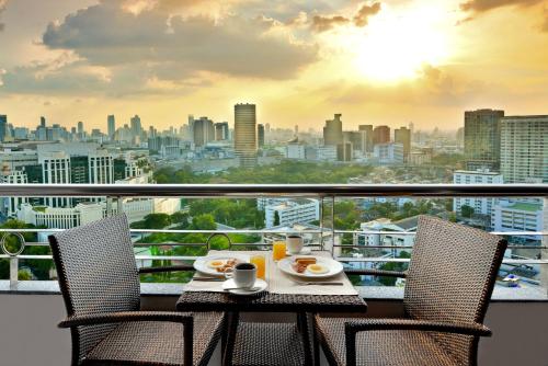 a table with food on a balcony with a view of a city at Centre Point Plus Hotel Pratunam in Bangkok