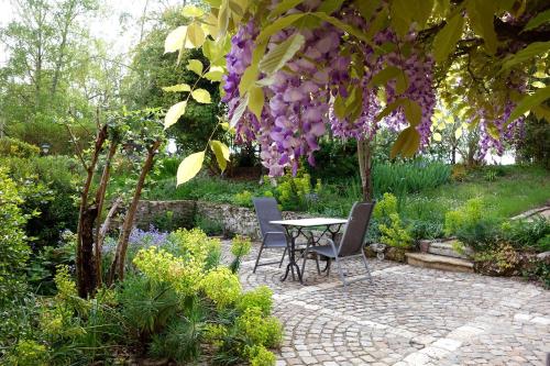 una mesa y sillas en un jardín con flores púrpuras en Les Jardins de Camelot, en Villegouge