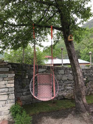 a pink swing hanging from a tree next to a stone wall at Garden Hotel Pasanauri since 1892 in Passanauri