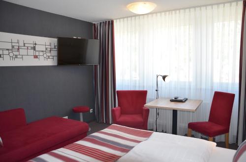 コッヘムにあるFlair Hotel am Rosenhügel - Garniのベッド1台と赤い椅子2脚が備わるホテルルームです。