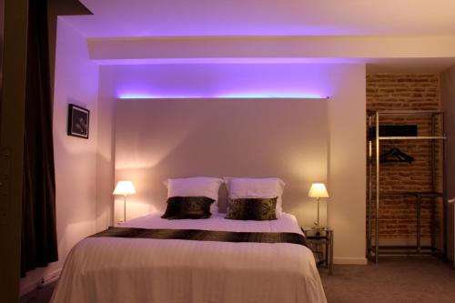 a bedroom with a bed with a purple light on it at Hôtel des Arts in Toulouse