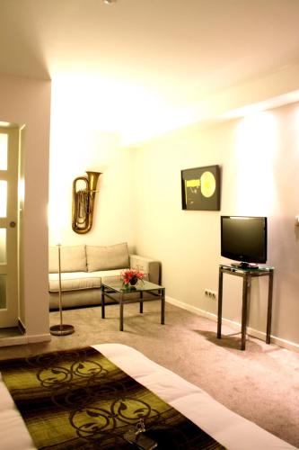 a living room with a couch and a tv at Hôtel des Arts in Toulouse