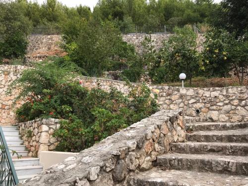 a stone retaining wall with stairs in a garden at Katarina Apartments Kefalonia - Sea View in Kefallonia