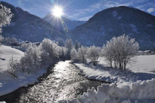 a river covered in snow with the sun in the background at Ferienwohnung Artur Wieser in Sankt Jakob in Defereggen